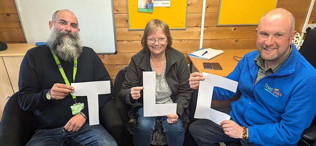 TLC counselling staff smiling and holding up the letters "T, L, C"